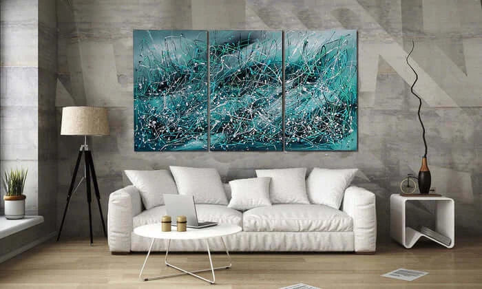 Modern Abstract Art triptych in a contemporary living room with white sofa and stylish decor.