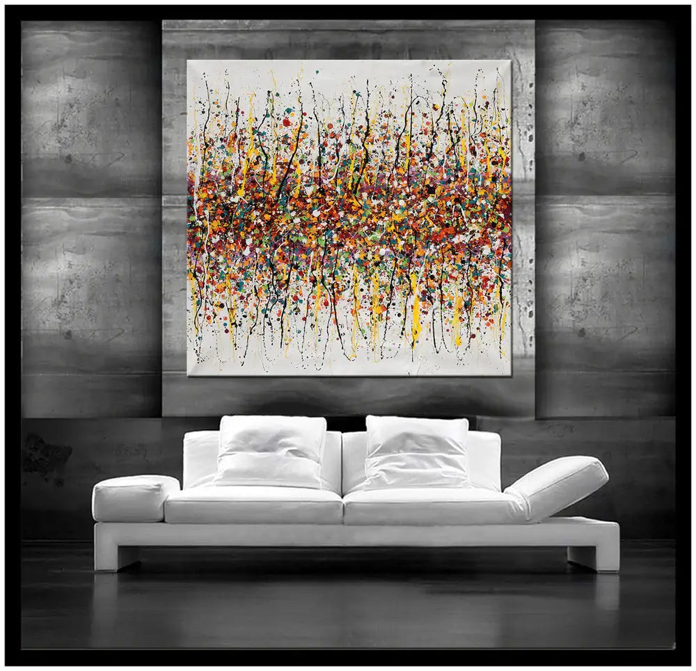 Splatter painting wall decor showcased above a modern white couch in a stylish interior setting.