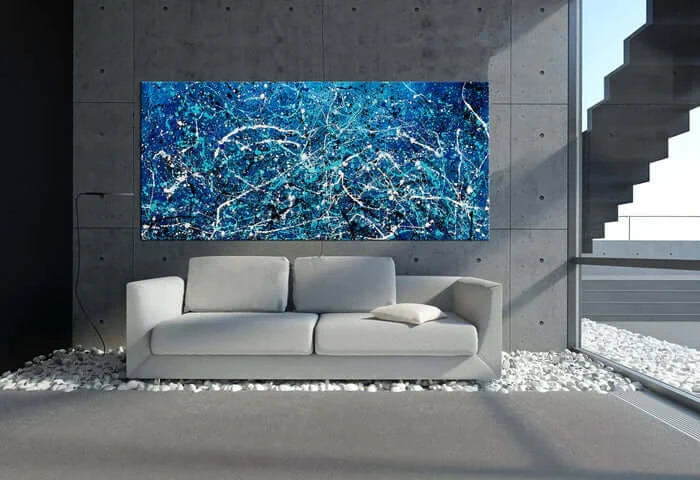 Abstract hand-painted art in vibrant blue hues displayed above a modern sofa in a stylish dining room.