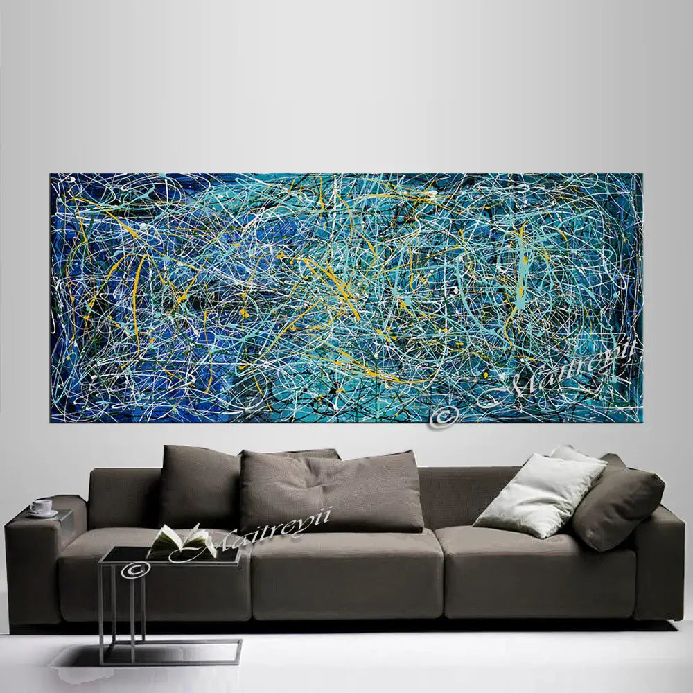 Large oil painting in Jackson Pollock Drip Style above a modern gray sofa, showcasing vibrant colors and abstract design.