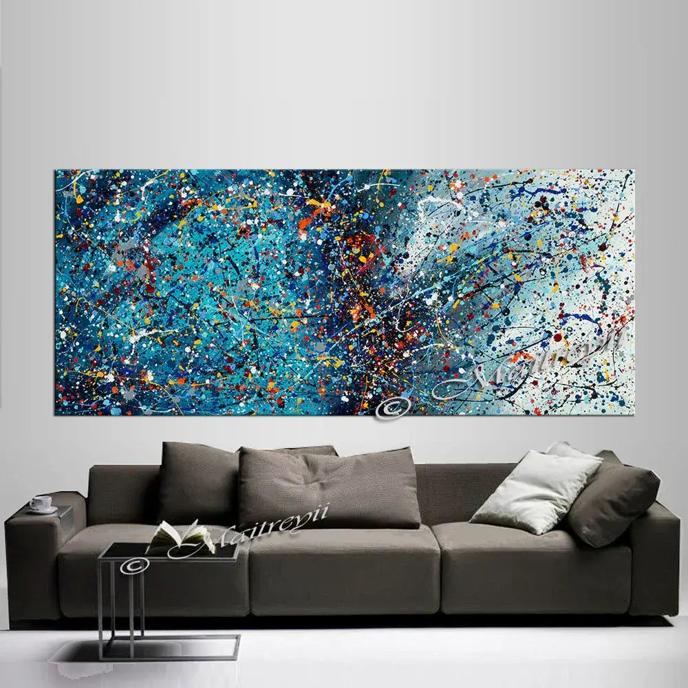 Blue abstract painting with vibrant splashes displayed above a modern sofa, enhancing contemporary decor.