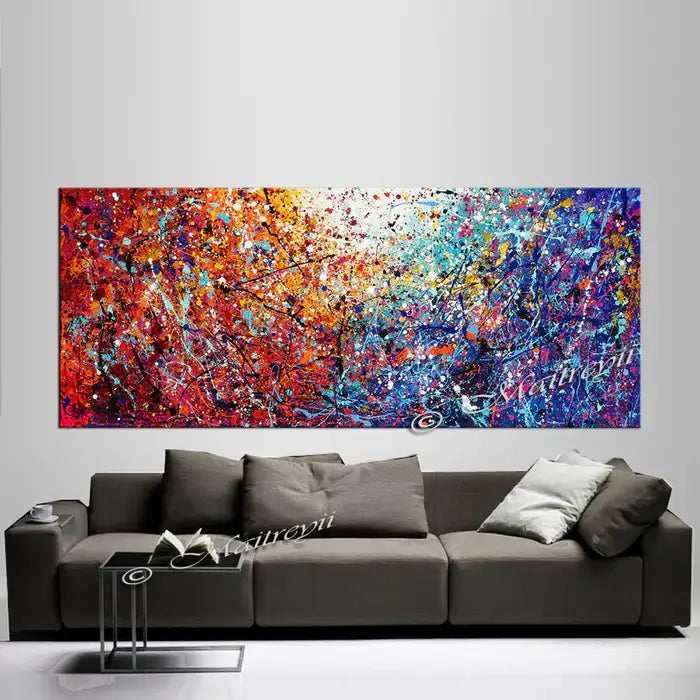 Painted abstract art displayed above a modern sofa, showcasing vibrant colors and dynamic textures on canvas.