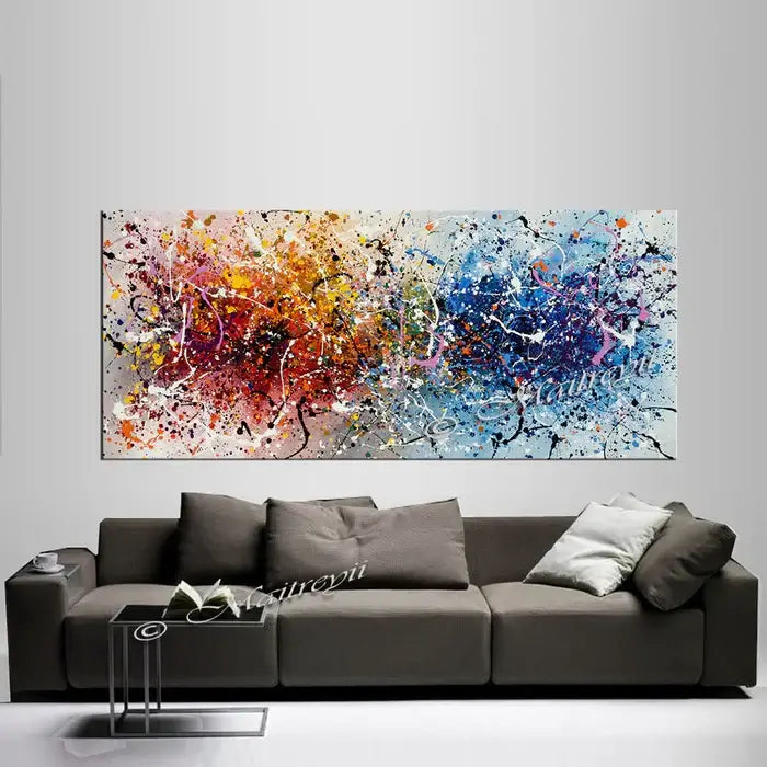 Vibrant hand-painted original canvas wall art in colorful splashes above a modern gray sofa, enhancing contemporary decor.